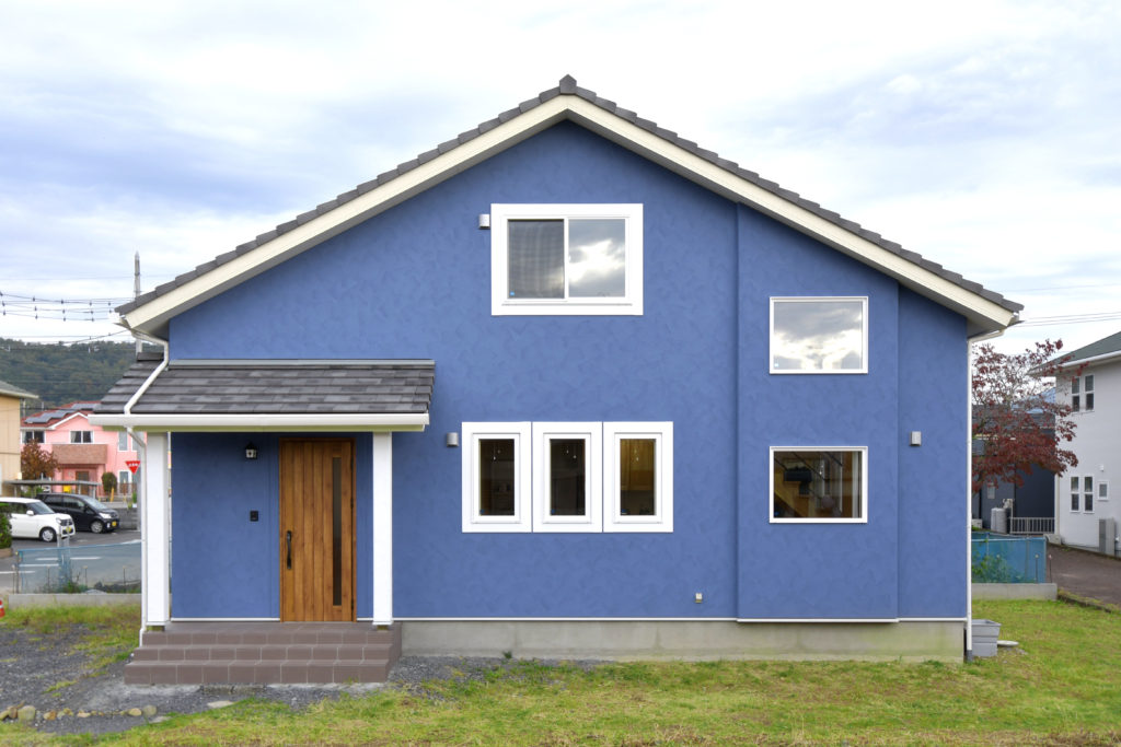 青い外壁の三角屋根の家。